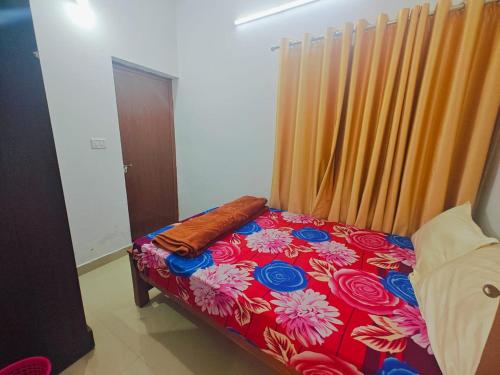 a small bedroom with a bed with a red and blue flowered bedspread at Ventos Tent Stay and Aframes in Anachal