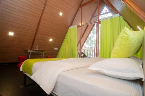a bedroom with a bed in a room with green curtains at Ventos Tent Stay and Aframes in Anachal