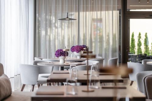 a dining room with tables and white chairs and flowers at Harmony Birštonas in Birštonas