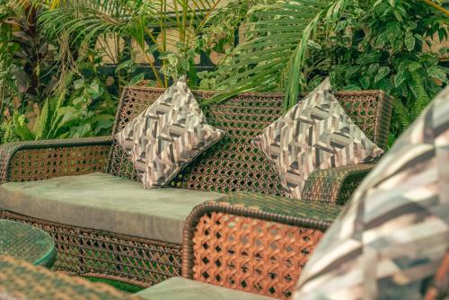 a wicker chair with two pillows on a patio at Joshean Apartments in Wakiso