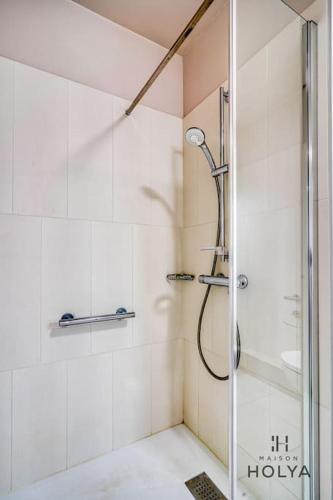 une douche avec une porte vitrée dans une salle de bain dans l'établissement Le Subtil - Aux portes de Paris - 365B, à Issy-les-Moulineaux