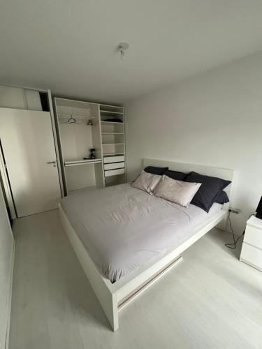 - une chambre blanche avec un grand lit blanc dans l'établissement Appartement cosy proche Paris, à Villepinte