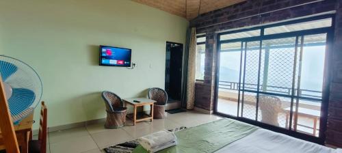 a room with a bed and a balcony with a television at RUDRA Retreat in Hawālbāgh