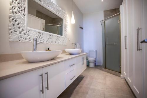a white bathroom with two sinks and a shower at Villa Les Sablons in Petit Raffray
