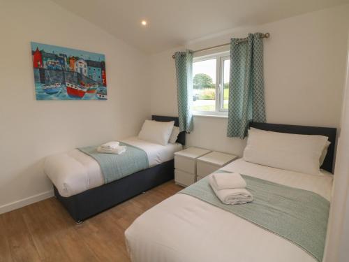 Un dormitorio con dos camas y una ventana. en Cove Lodge, en Ilfracombe
