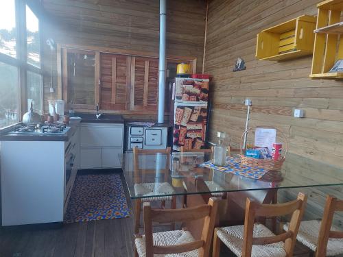 une cuisine avec une table en verre et des chaises. dans l'établissement Chalé com banheira de hidromassagem e mesa de sinuca, à Bom Jardim da Serra