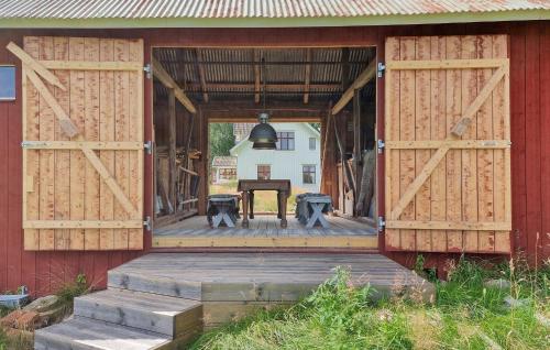 a barn with wooden doors and a table on a porch at Awesome Home In Frändefors in Frändefors