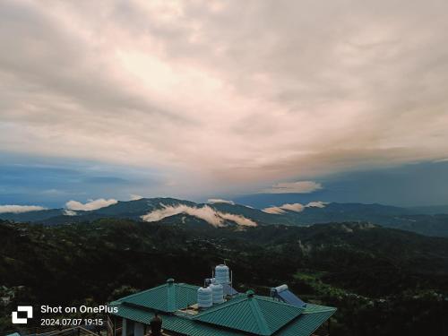 a view of a mountain with clouds in the sky at RUDRA Retreat in Hawālbāgh