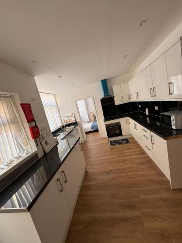 a large kitchen with white cabinets and black counter tops at Pinnacle Hotel & Suites formerly Jean Martyn Hotel Near Central Blackpool, Near Beach & Attractions in Blackpool