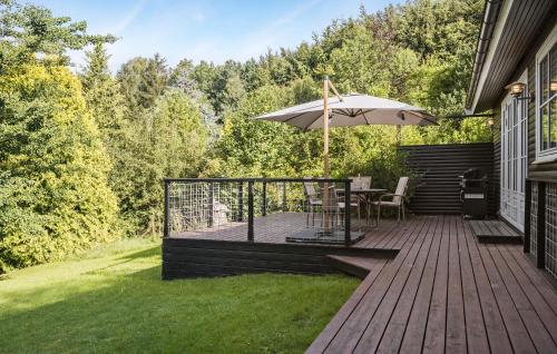 a wooden deck with a table and an umbrella at Two-Bedroom Pet Friendly Home In Holbæk in Holbæk