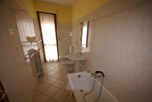La salle de bains est pourvue d'un lavabo, de toilettes et d'une baignoire. dans l'établissement Hotel Londra, à Acceglio
