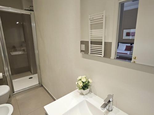 a bathroom with a toilet and a sink with a vase of flowers at Loger Confort Residence & Apartments in Turin