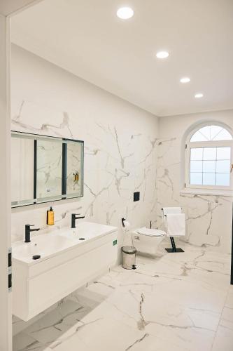 a white bathroom with two sinks and a toilet at Lacul Verde Resort in Ploieşti