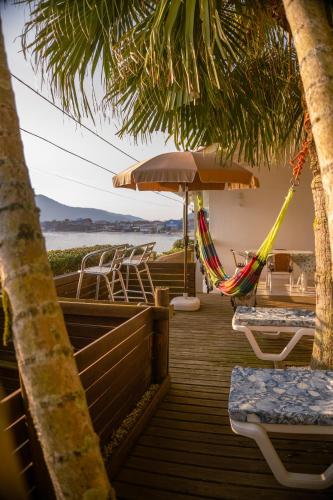 a deck with two hammocks and chairs and the beach at Casa no Paraíso - Pântano do Sul - Florianópolis in Florianópolis