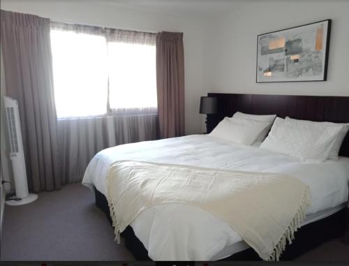 a bedroom with a large white bed with a window at Modern 2BR 2BA Close to CBD - Hosted by Canstay in Canberra
