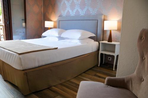 a bedroom with a bed with white pillows and a chair at Hôtel Le Golfe Ecolabel EU in Porto Ota