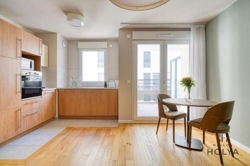 une cuisine avec une table et des chaises dans une pièce dans l'établissement Le Spacieux - En bordure de Paris - 366B, à Issy-les-Moulineaux