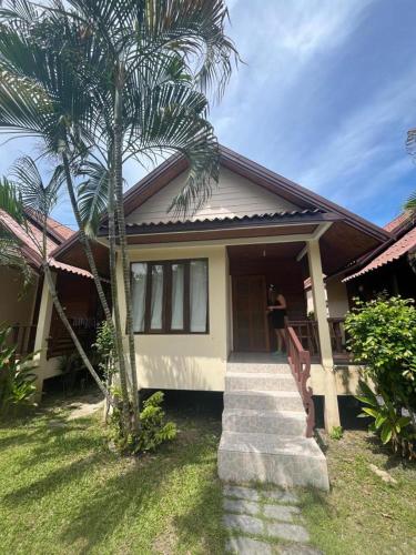 a person standing outside of a house with a palm tree at Apache Bar Haad yao in Haad Yao