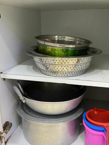 three pans sitting on a shelf in a kitchen at SRT HOMELY STAY WITH All AMENITIES in Hyderabad