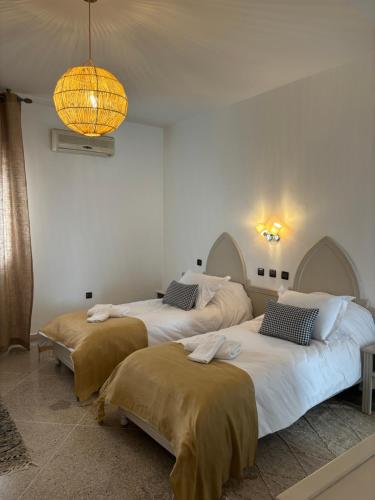 three beds in a room with a chandelier at Résidence Mer et soleil in Agadir