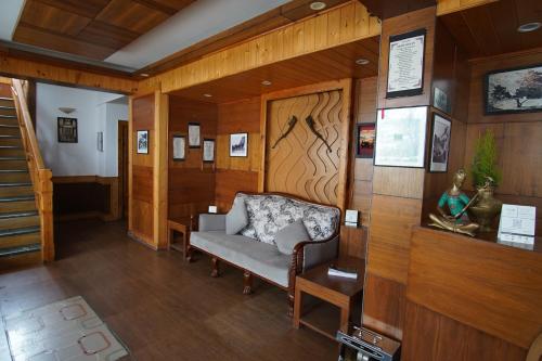a living room with a chair and wooden walls at Vivaan The Sunrise in Manāli