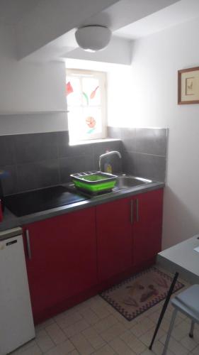 une cuisine avec des armoires rouges et un évier dans l'établissement Eole, à Saint-Malo