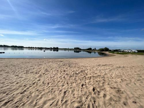 a beach with footprints in the sand and a body of water at Ferienhaus Lathum früher Chalet Familienzeit in Lathum