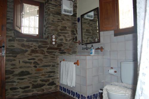 a bathroom with a toilet and a stone wall at Casa Fina in Bubión