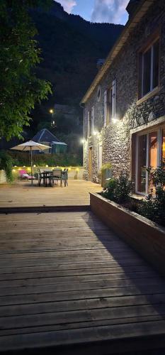 a building with a patio with a table and an umbrella at Gîte L'Ostau 4 étoiles Les Échappées Belles in Antignac