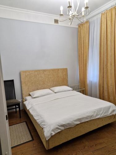a bedroom with a bed with white sheets and a chandelier at Затишна квартира на Майдані Незалежності in Kyiv