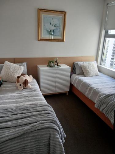 a bedroom with two beds and a teddy bear sitting between them at Wings 2 Bedroom Apartment in Gold Coast