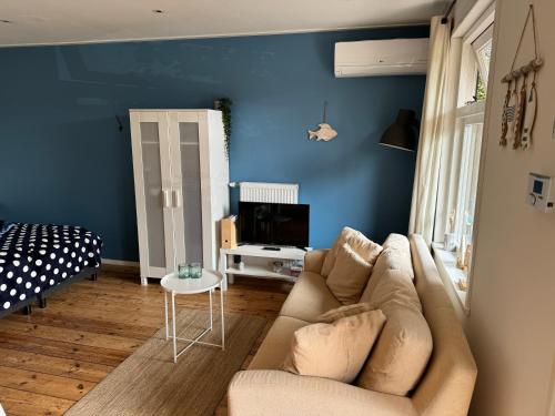 a living room with a couch and a blue wall at Studio appartement 1nul9Noord in Renesse