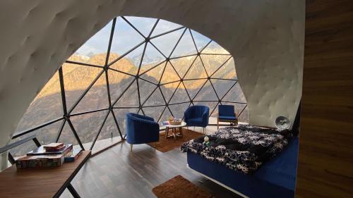 a room with a bed and a large glass window at We Are Made Of Stories in Joshīmath