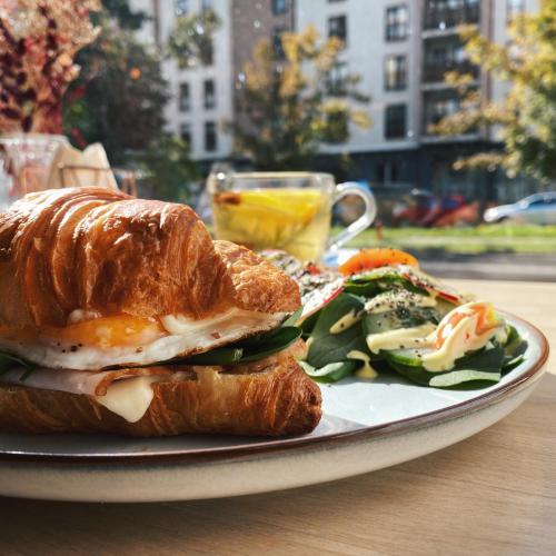 a plate with a croissant sandwich and a salad at New Adler Bed & Breakfast in Łódź