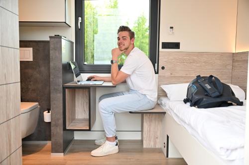 a man sitting at a desk in a bedroom at Roatel Emden A31 my-roatel-com in Emden