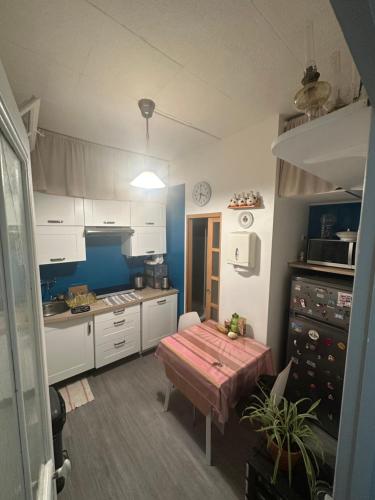 une cuisine avec des armoires blanches et une table à l'intérieur dans l'établissement Appartement Paris 18, à Paris