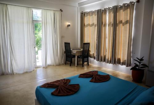 a bedroom with a blue bed and a table with chairs at Singhe House in Dickwella