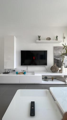 a white living room with a remote control on a couch at Fuertevillage in Costa Calma