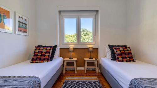 two beds in a room with a window at Charming Belém 3BDR Property by LovelyStay in Lisbon