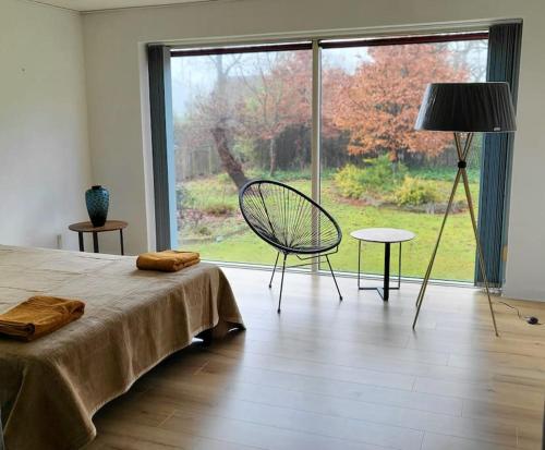 a bedroom with a bed and a chair and a large window at Billund Centre Rica House,500m to Lego House in Billund
