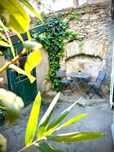 2 chaises et une table à côté d'un mur en pierre dans l'établissement Cosy T2 RDC avec extérieur privatif, à Nantes