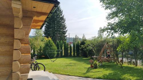a person sitting on a swing in a garden at Chata Czarny Kot z jacuzzi i sauną in Janowice Wielkie