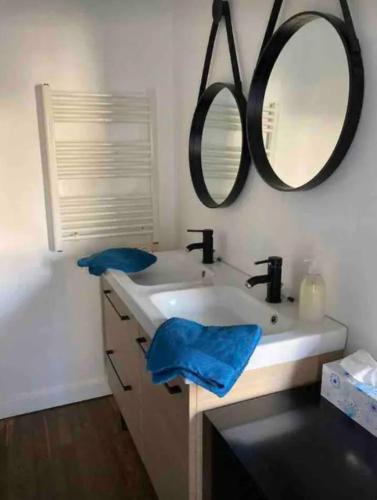 une salle de bain avec un lavabo et un miroir au mur dans l'établissement Maison de vacances bord de mer à Lion sur Mer, à Lion-sur-Mer