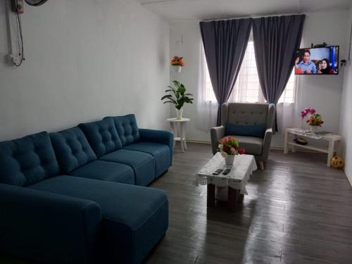 a living room with a blue couch and a table at Homestay Mak Serting Tengah in Batu Kikir