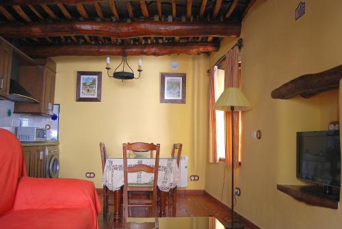 sala de estar con mesa y cocina con TV. en Casa El Rincón del Ángel, en Bubión