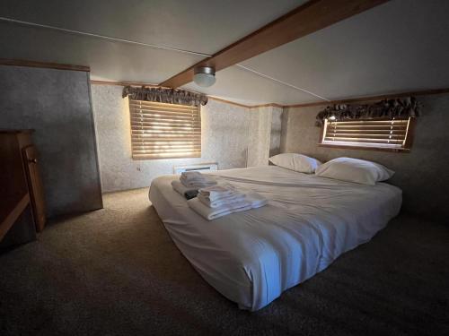 a bedroom with a large white bed with two windows at Cabin 62 in Almont