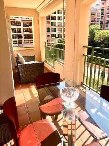a balcony with a glass table and chairs at Monaco, elegant & quiet renovated apartment, with terrace & pool, 15min walk to Port Hercule in Monte Carlo