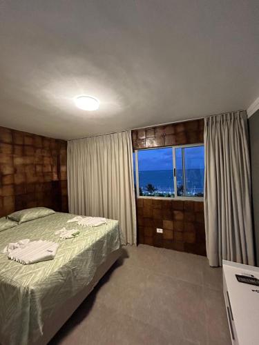 a bedroom with a bed and a large window at APARTAMENTO ENCANTADOR NA BEIRA-MAR DE MACEIÓ in Maceió