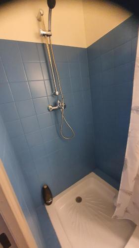 La salle de bains carrelée de bleu est pourvue d'une douche et d'une baignoire. dans l'établissement Charmant Studio proche Faculté CHU prix imbattable, à Dijon