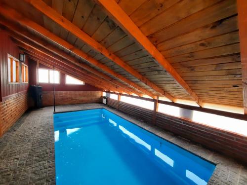een zwembad in een gebouw met een houten plafond bij Alentue in Dina Huapi